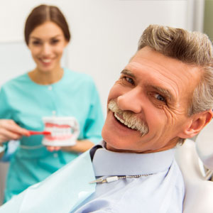 Happy elderly man on a review of a dentist, sitting in a chair