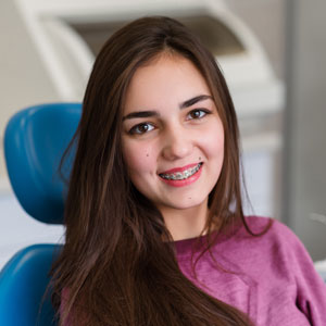 Beautiful girl with braces smiles in dentistry