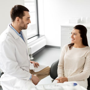 Male dentist talking to female patient and discussing teeth treatment at dental clinic office