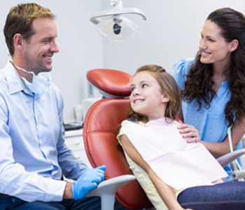 Dentist interacting with mother and daughter