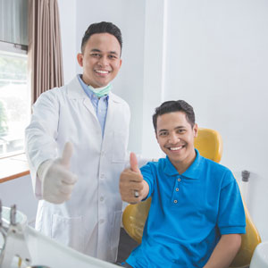 Portrait of dentist and patient giving thumbs up at dentist office
