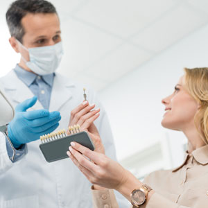 Doctor showing tooth implants to female patient in modern dental clinic