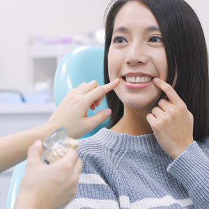 Woman pointing at her teeth and talking with dentist at dental clinic