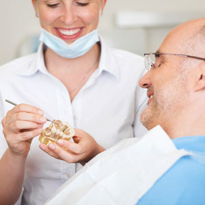 Smiling Female Dentist explaining artificial teeth