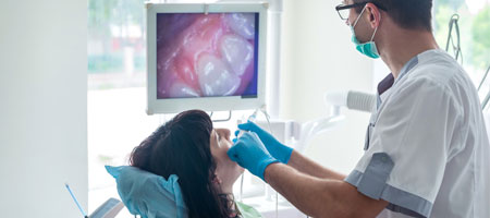 Doctor examining patient's teeth using intraoral camera 