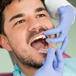 Dentist placing invisible braces to patient's mouth