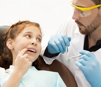 Little girl visiting dentist pointing at aching tooth in her mouth in dental emergency