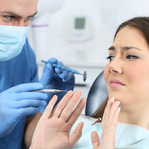 Scared patient with a doctor trying to examine her in a dentist office