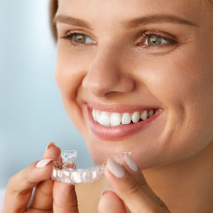Smiling woman with white teeth holding teeth whitening tray