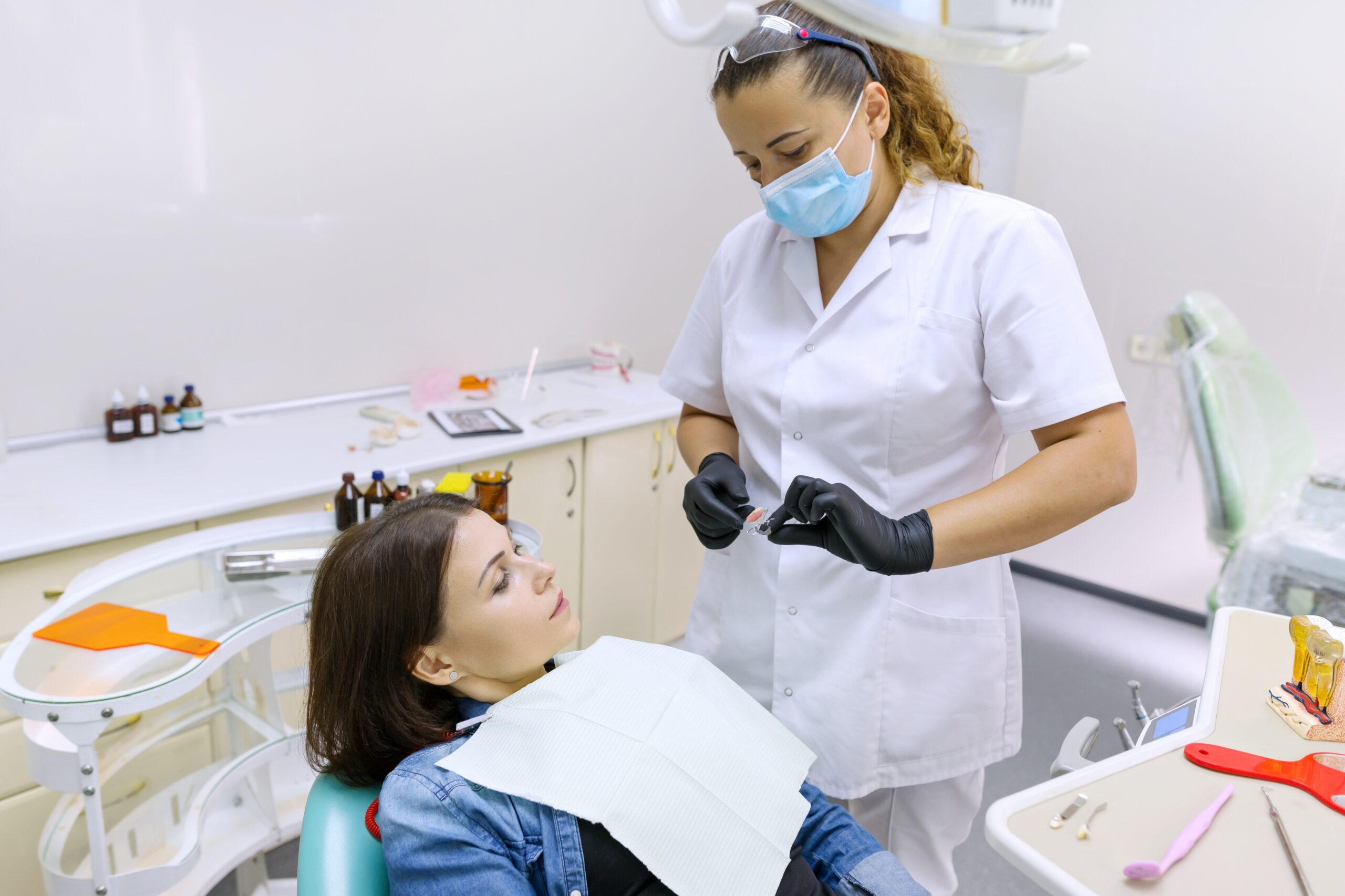 Partial denture, mature woman patient sitting in dental chair, doctor dentist doing dental prosthesis.